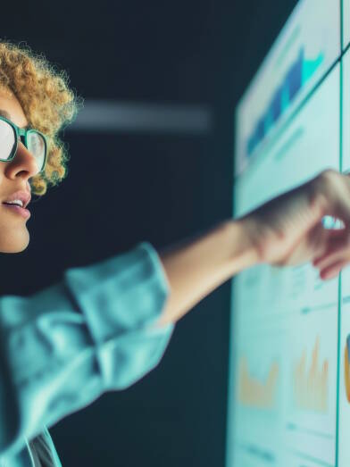 Analytical businesswoman presenting data on a large interactive display